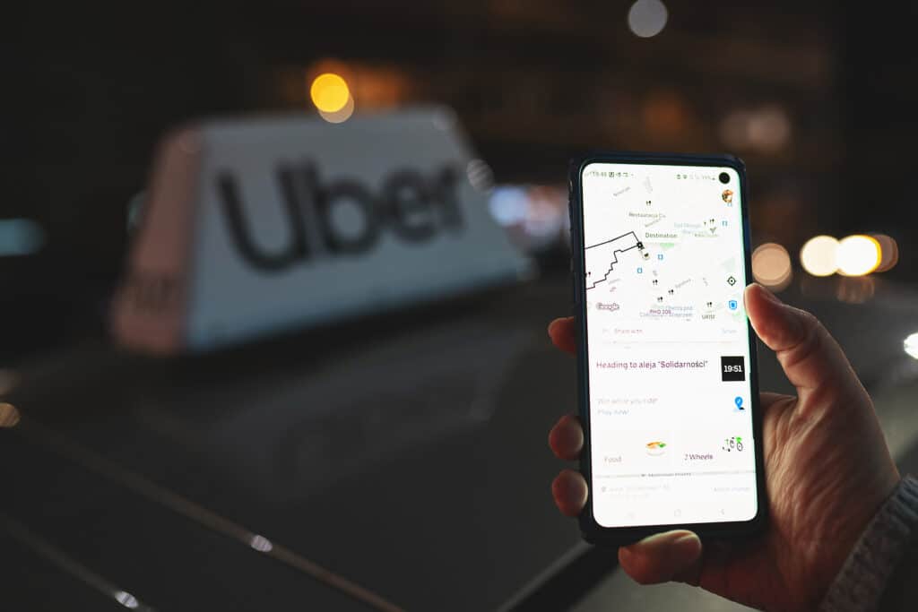 Uber App Displayed On Smartphone Held In Hand In Front Of Uber T