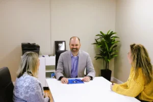 A lawyer sitting with two clients in an office, discussing their case.